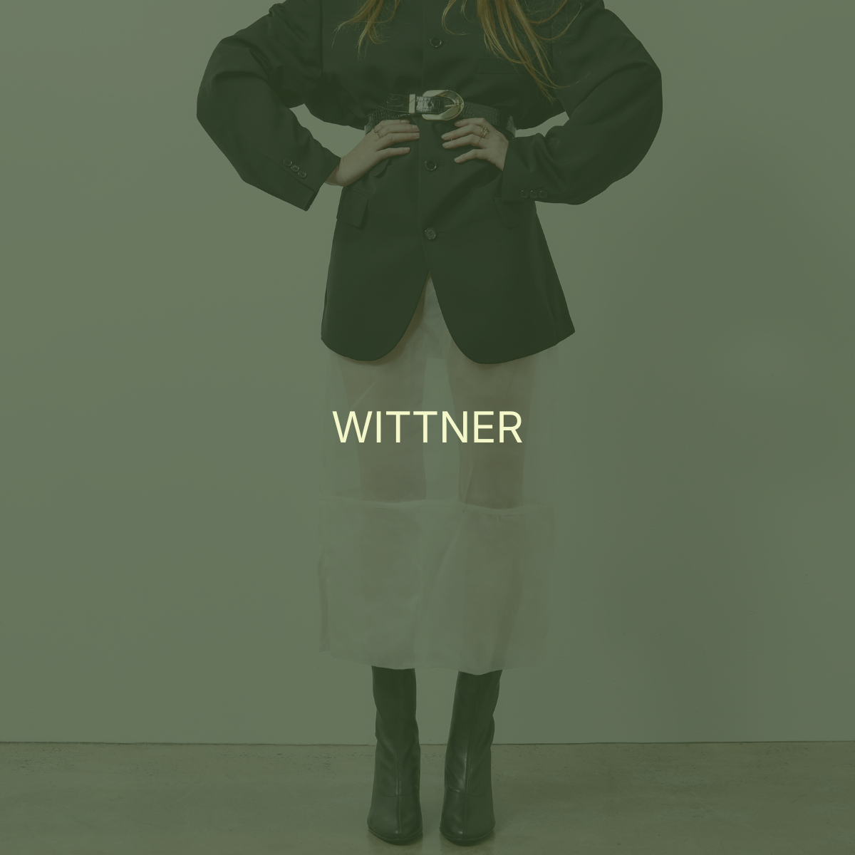 Person wearing a black blazer and beige pants with the word "WITTNER" in front.