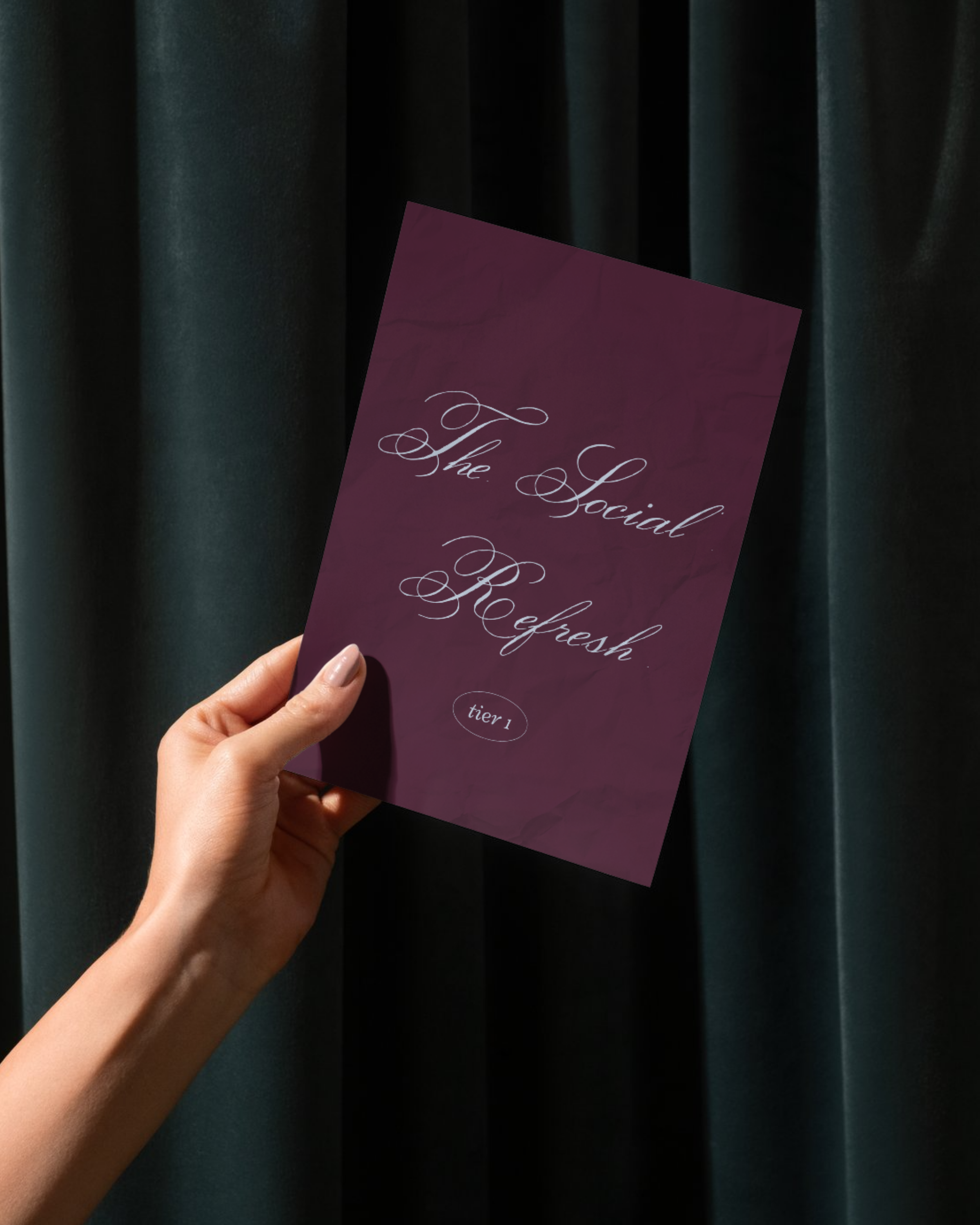 A hand holding a purple placard that reads "The Social Refresh" in elegant white script, with a dark curtain background.
