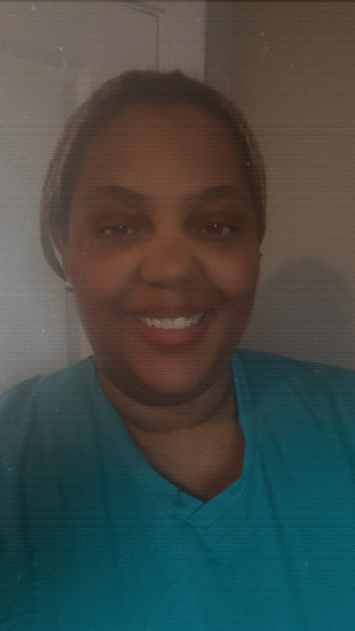 Smiling person wearing a teal shirt in a close-up portrait