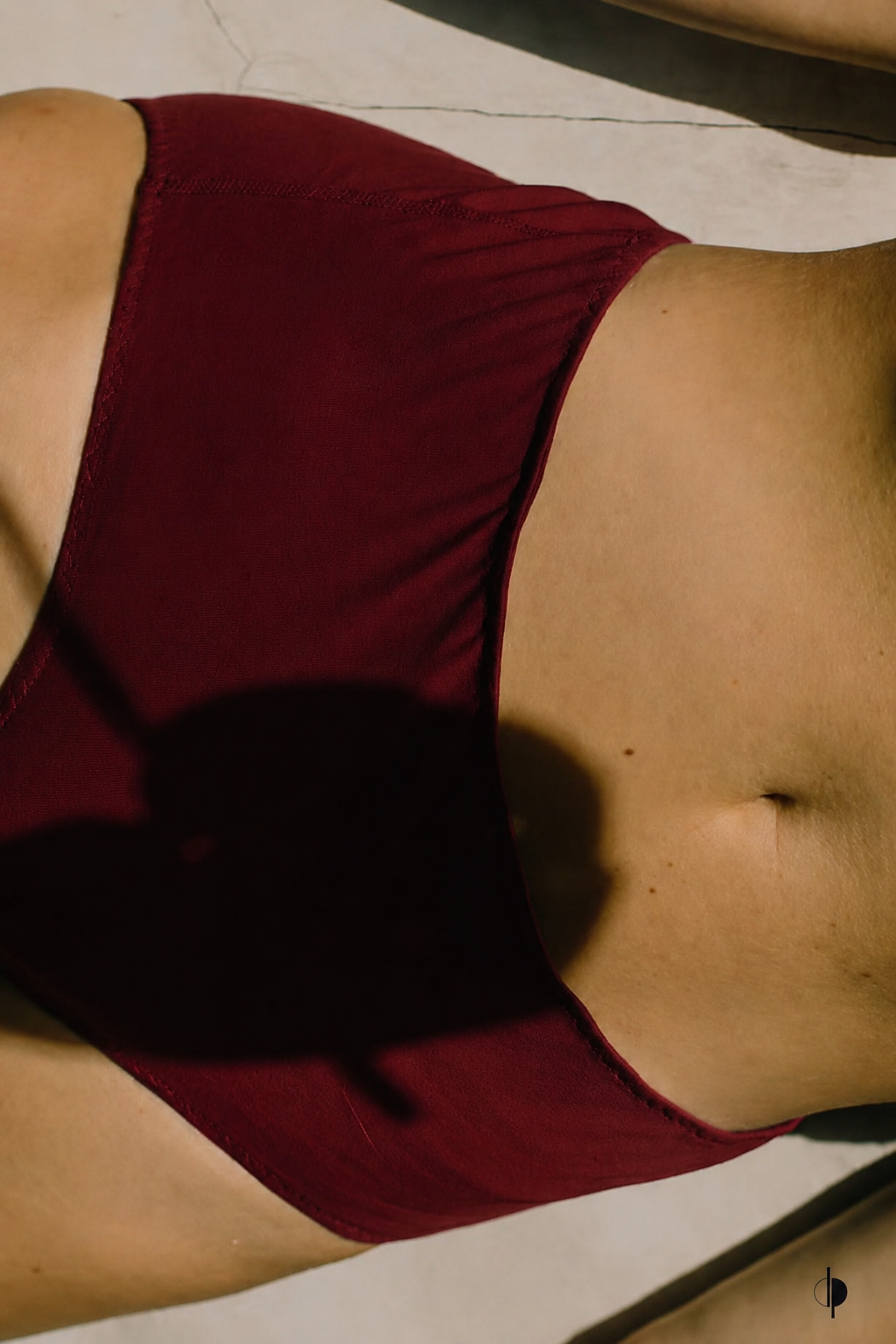 Close-up of a person's midsection wearing red underwear, showing the lower stomach and hip area.