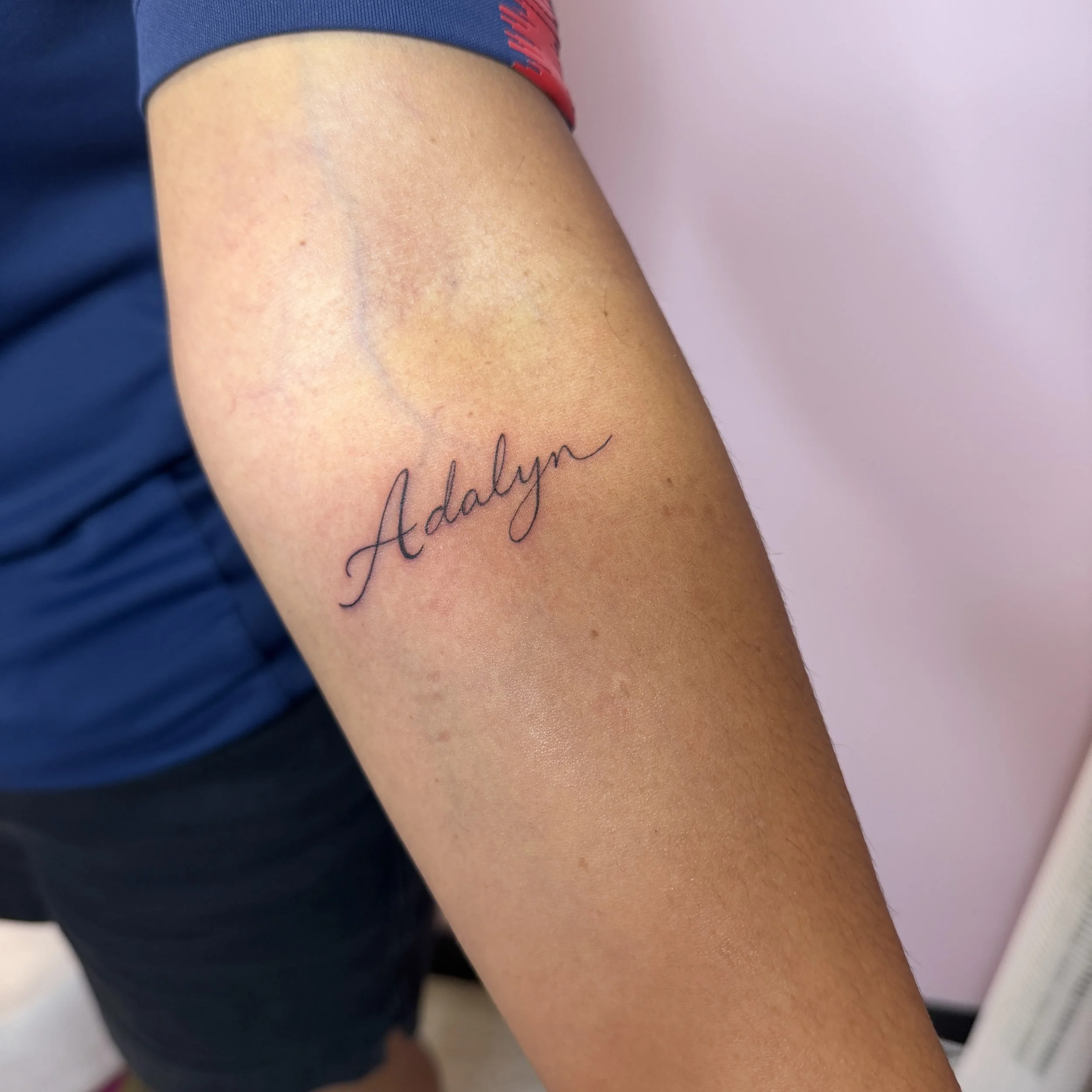 Close-up of a person's arm with the name "Addalyn" tattooed in cursive writing.