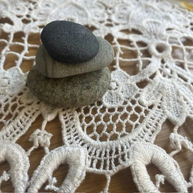 Three stacked stones on a decorative lace tablecloth.