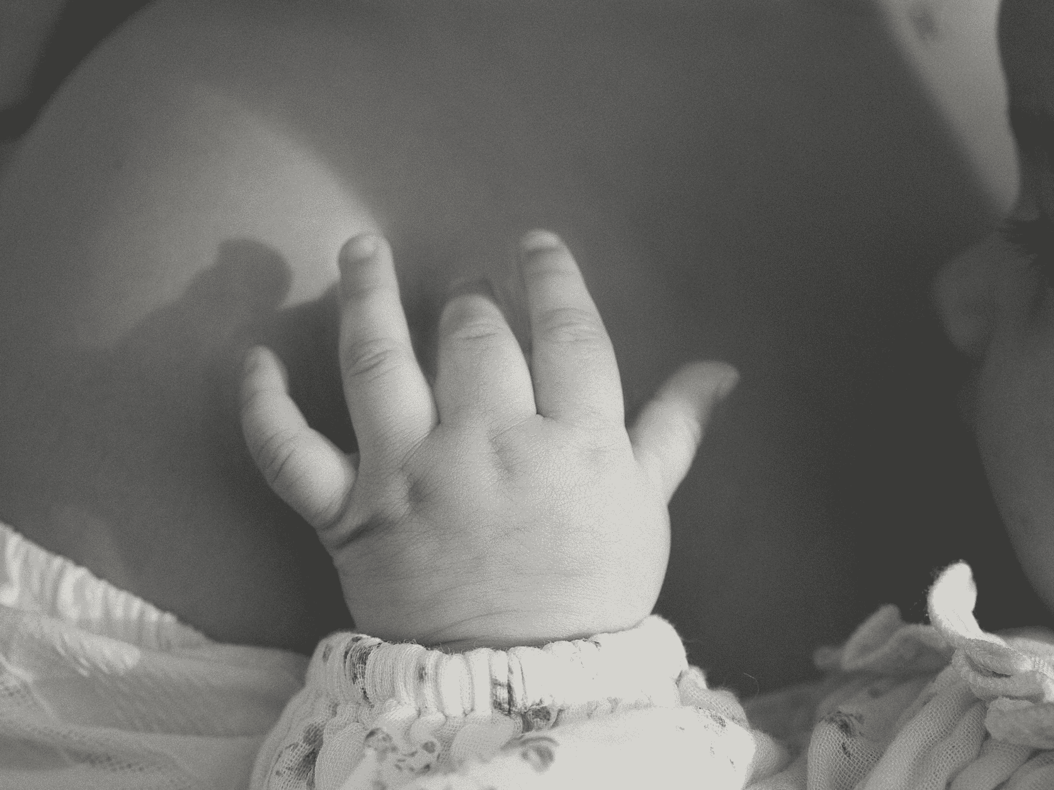 A baby's hand tickling their mother's shoulder.