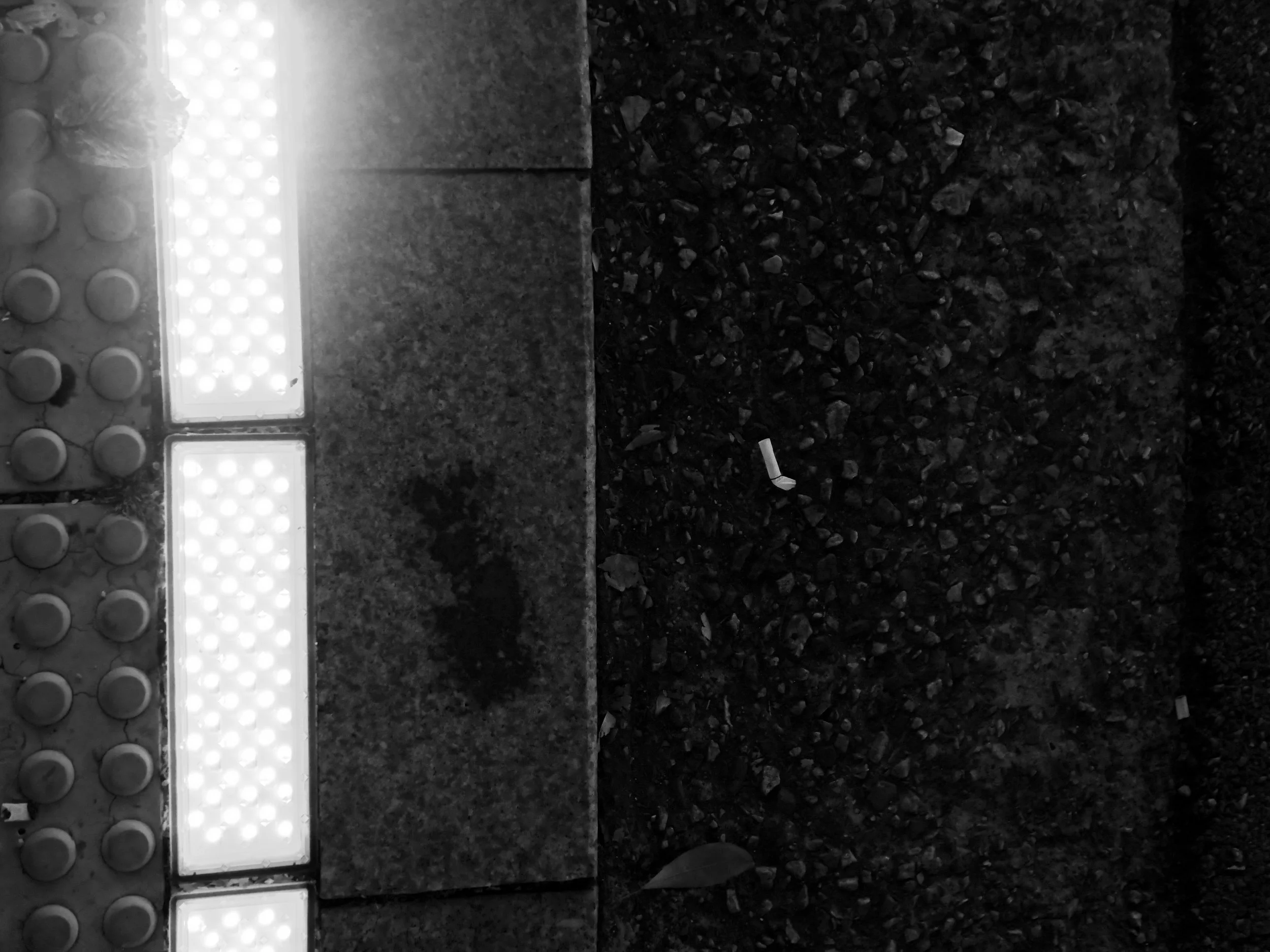 Close-up of a wall with bright LED lights and a section of textured dark gravel or small rocks on the ground.