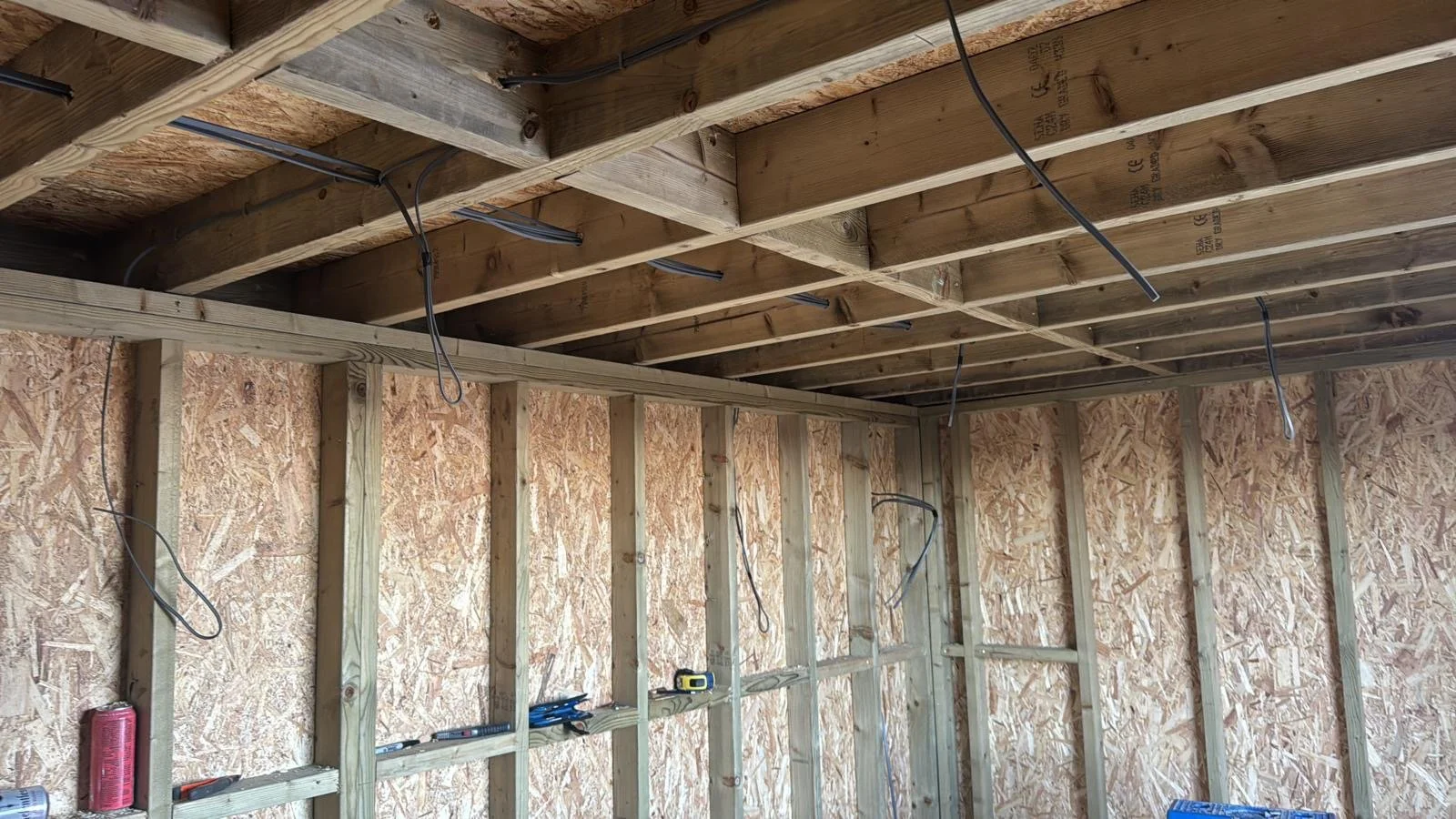 Interior of a building under construction with exposed wooden framing and electrical wiring.