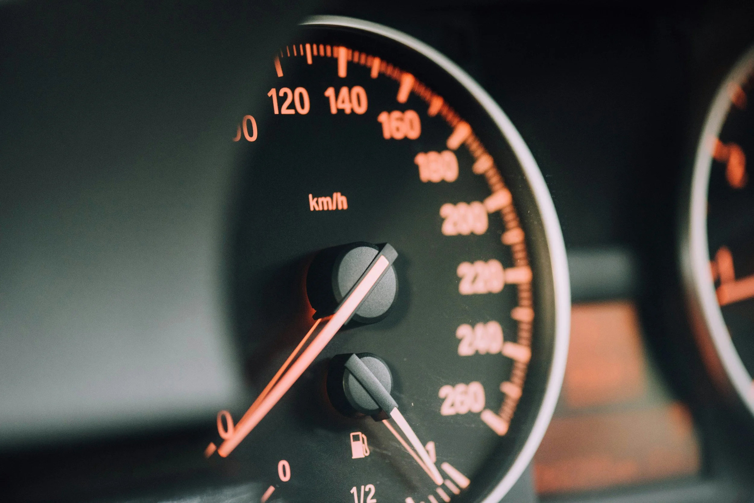 Close-up of a car's speedometer and fuel gauge, showing a speed of approximately 20 km/h and a nearly empty fuel tank.