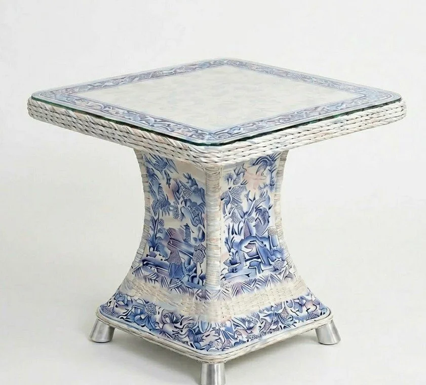 A decorative side table with a blue and white pattern, featuring a glass top and metal legs.