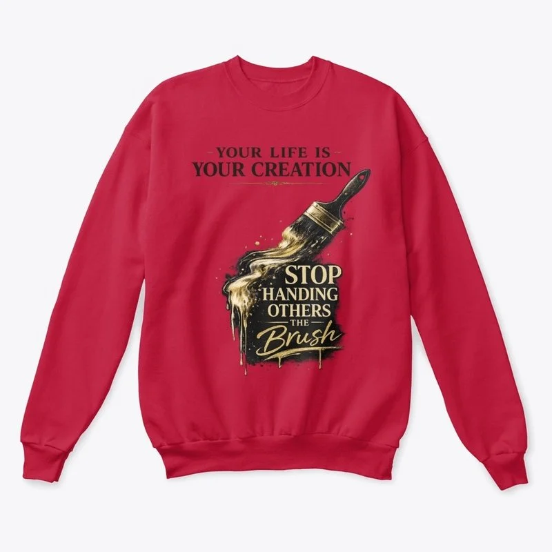 Red sweatshirt with a graphic of a paintbrush and paint splatters. The text reads 'Your life is your creation' at the top and 'Stop handing others the brush' at the bottom, emphasizing self-empowerment.