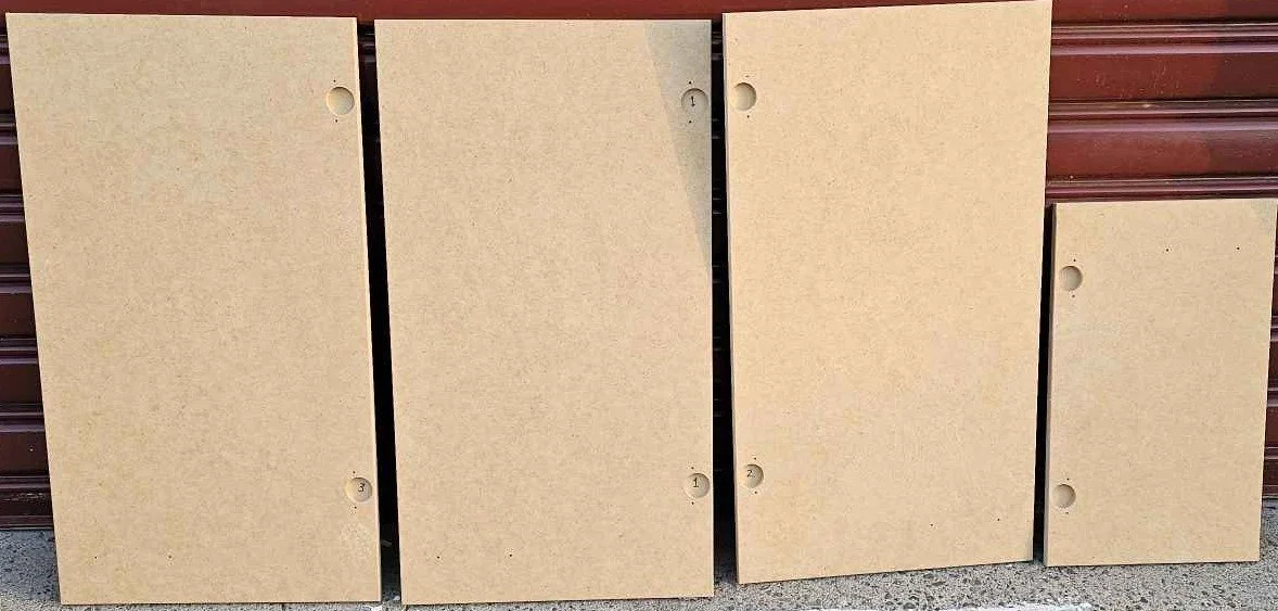 Four beige-colored rectangular panels leaning against a brown garage door, with holes near the edges.