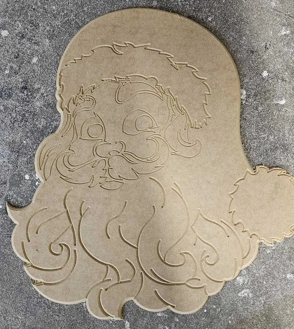 Outline of Santa Claus's face and beard carved into a piece of wood.