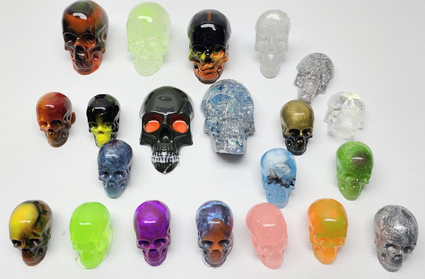 Colorful skull-shaped resin figurines arranged on a white surface.