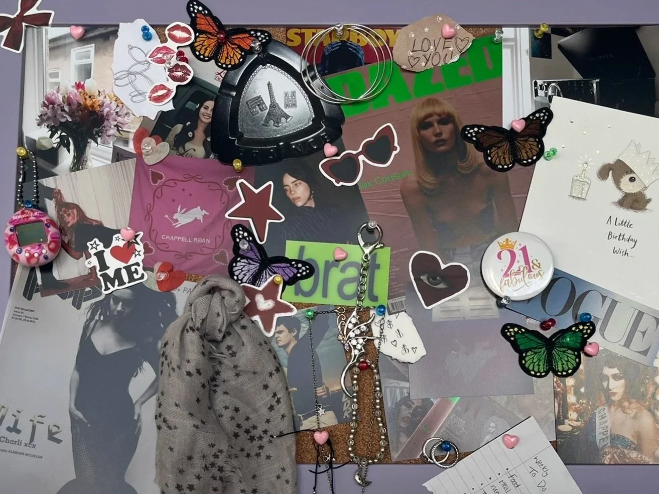 A collage of photos, stickers, and accessories on a bulletin board, featuring images of women, butterflies, lip prints, and various decorative items such as pins, rings, and handwritten notes.