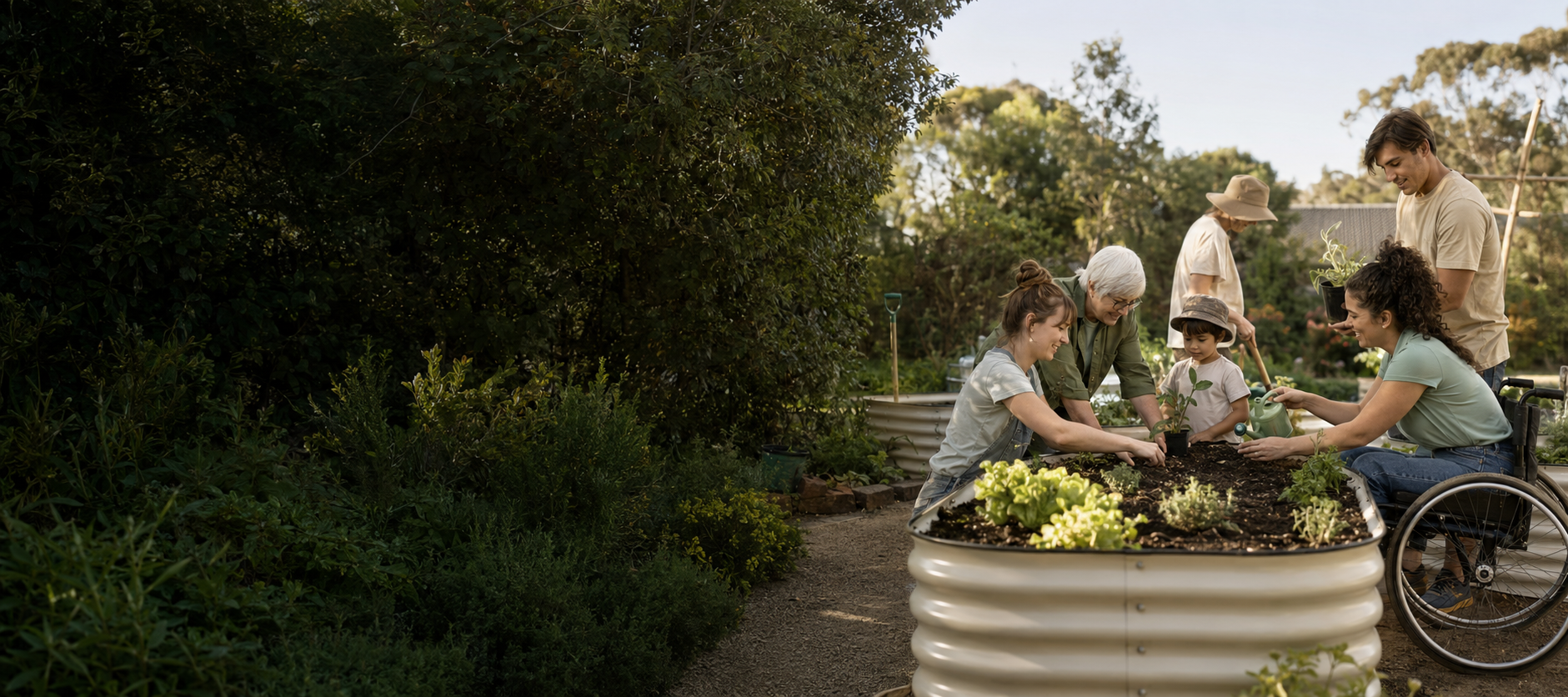 Group of people gardening together outdoors, including a woman in a wheelchair watering plants, a young girl planting a seedling, an elderly woman, and others working together on a garden bed with plants and flowers.