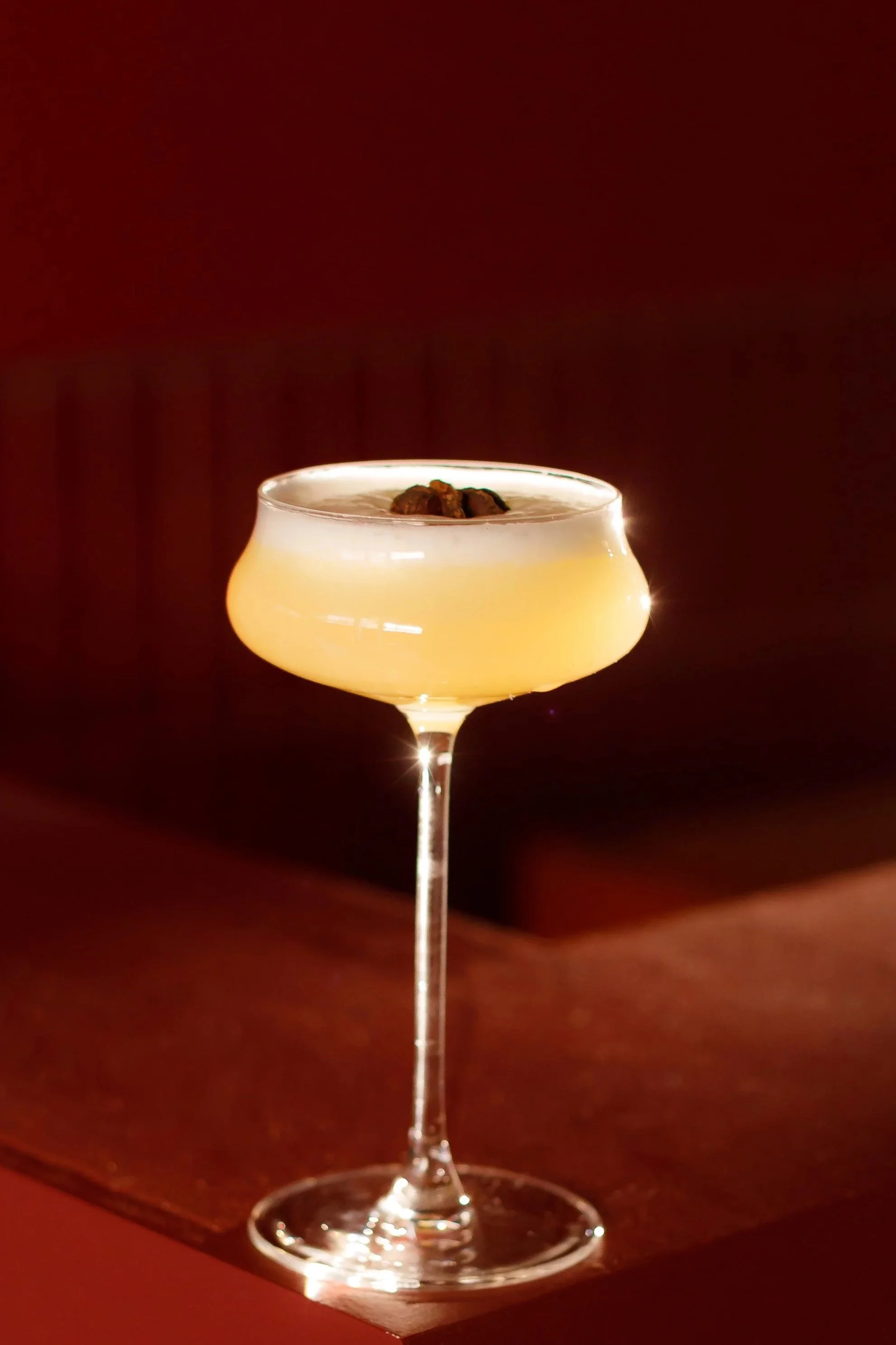 A cocktail in a coupe glass garnished with three dark berries.