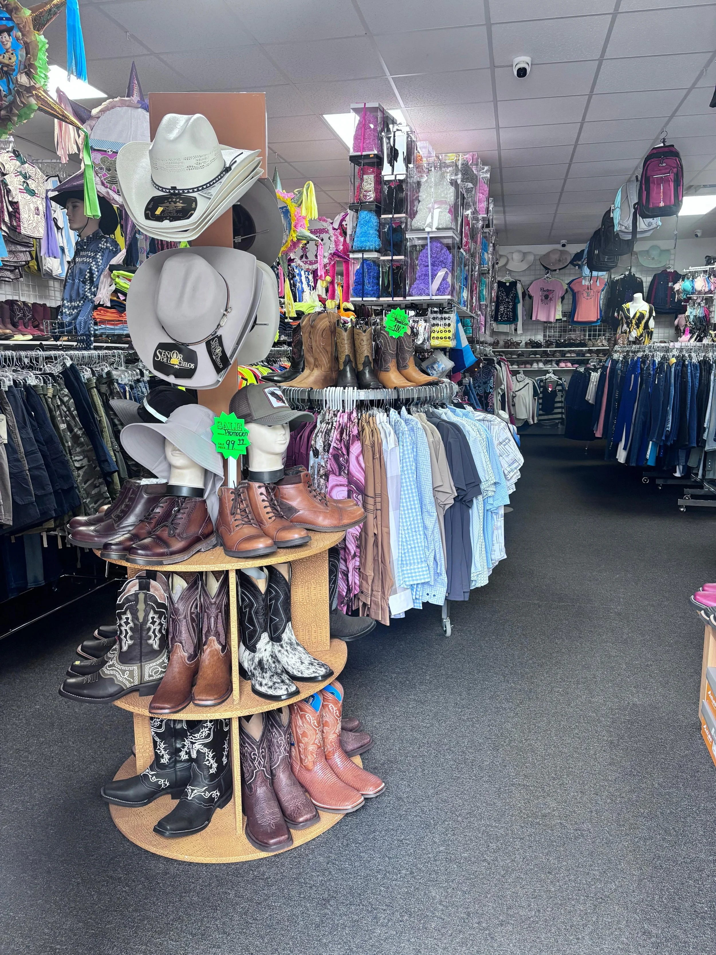 Clothing store with cowboy boots, hats, and western-style apparel displayed on mannequins and racks.
