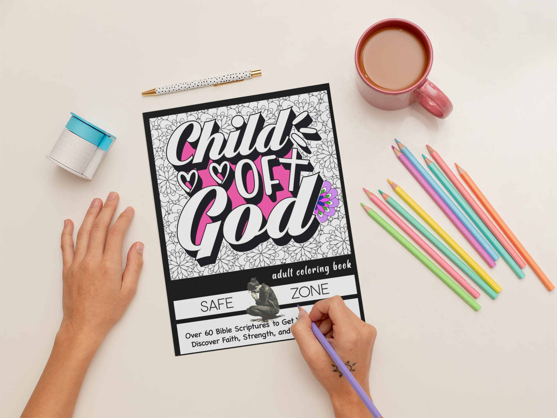 A person coloring a Bible coloring book titled 'Child of God' with a purple colored pencil. The table has a pink coffee mug, a small blue and white container, a polka-dotted pen, and a set of colorful pencils.
