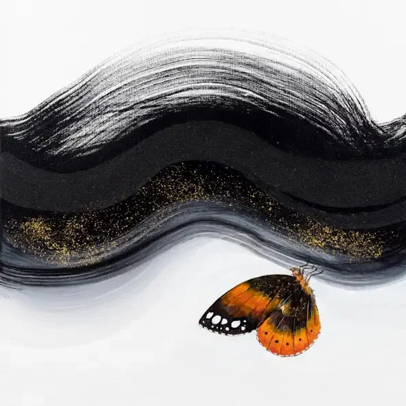 A butterfly with orange and black wings resting below black brush strokes and gold specks on a white background.