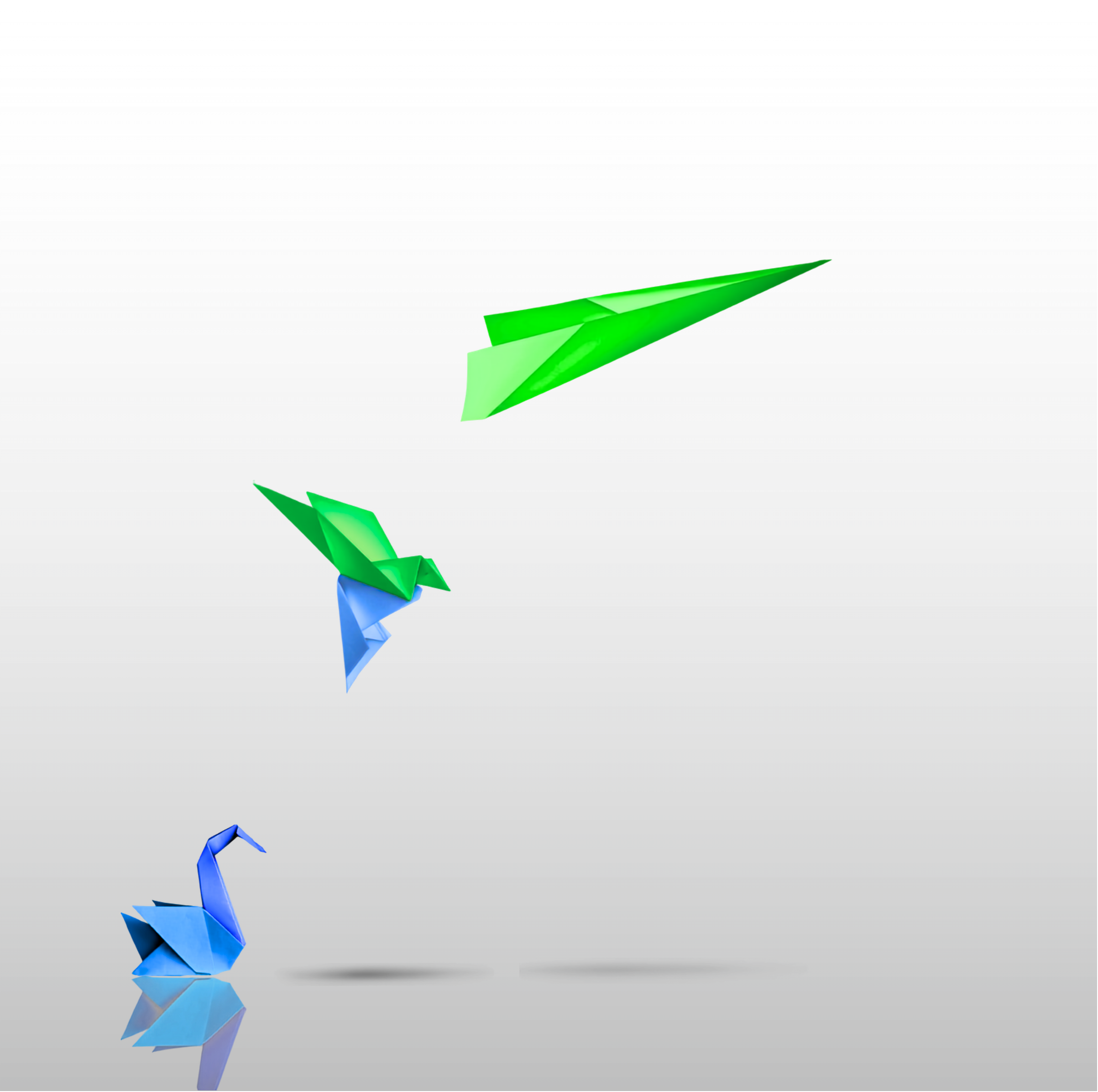 Colorful origami paper cranes with green and blue papers, reflecting on a dark surface.