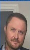 A man with dark hair and a beard, looking at the camera.