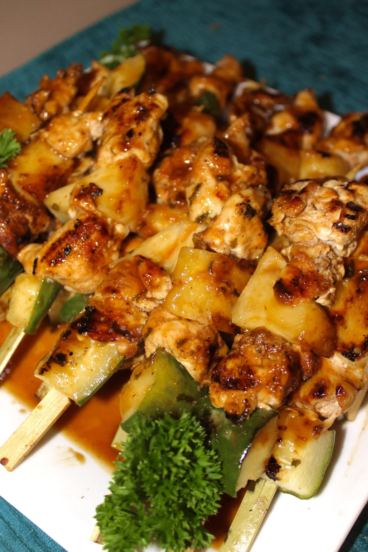 Close-up of grilled chicken and vegetable skewers garnished with parsley on a white plate.
