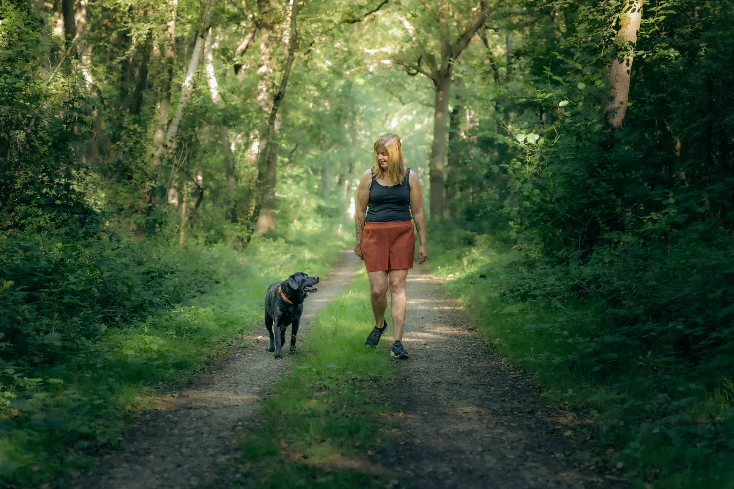 Frau geht mit ihrem Hund im Wald spazieren
