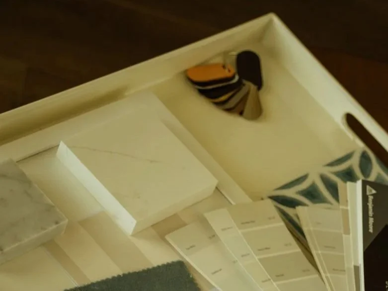 Interior design materials, samples, and project resources arranged on a tabletop during the design planning process.