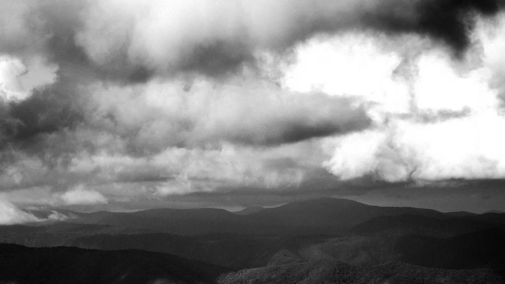 Black and white landscape of mountains under cloudy sky