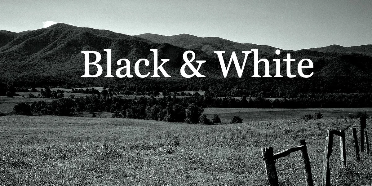 Black and white landscape photograph of rolling hills with a fence in the foreground and the words "Black & White" overlaid.
