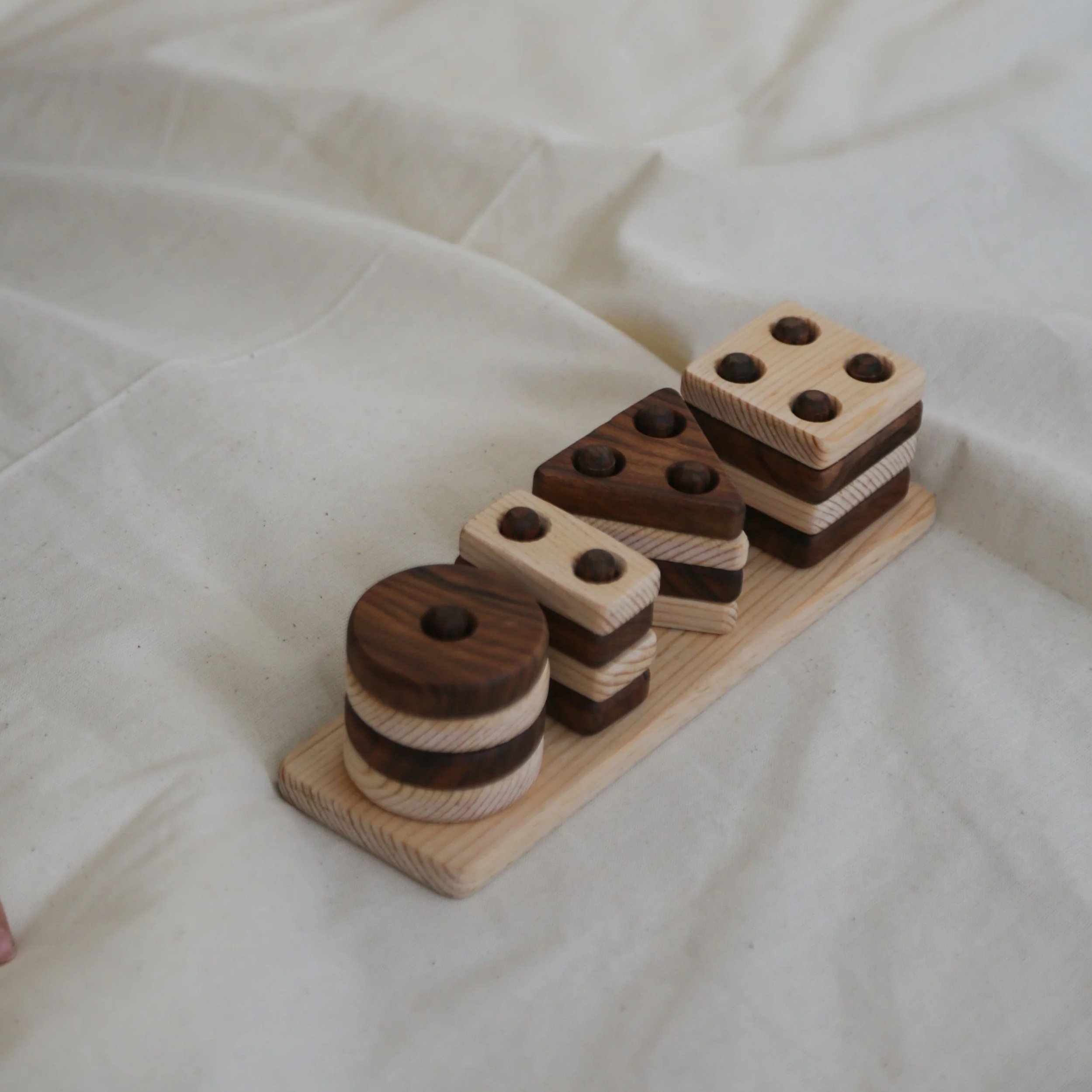 Stacked wooden domino pieces, some with dark circular dots, on a light surface.