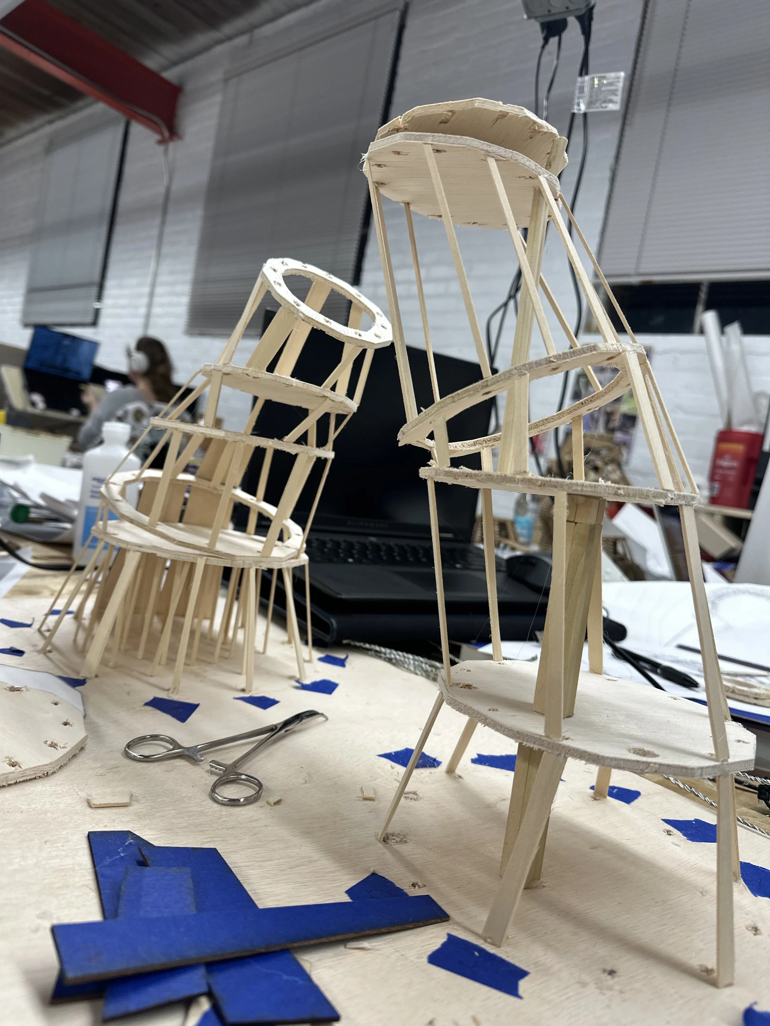 Wooden model of a structure in progress on a workbench.