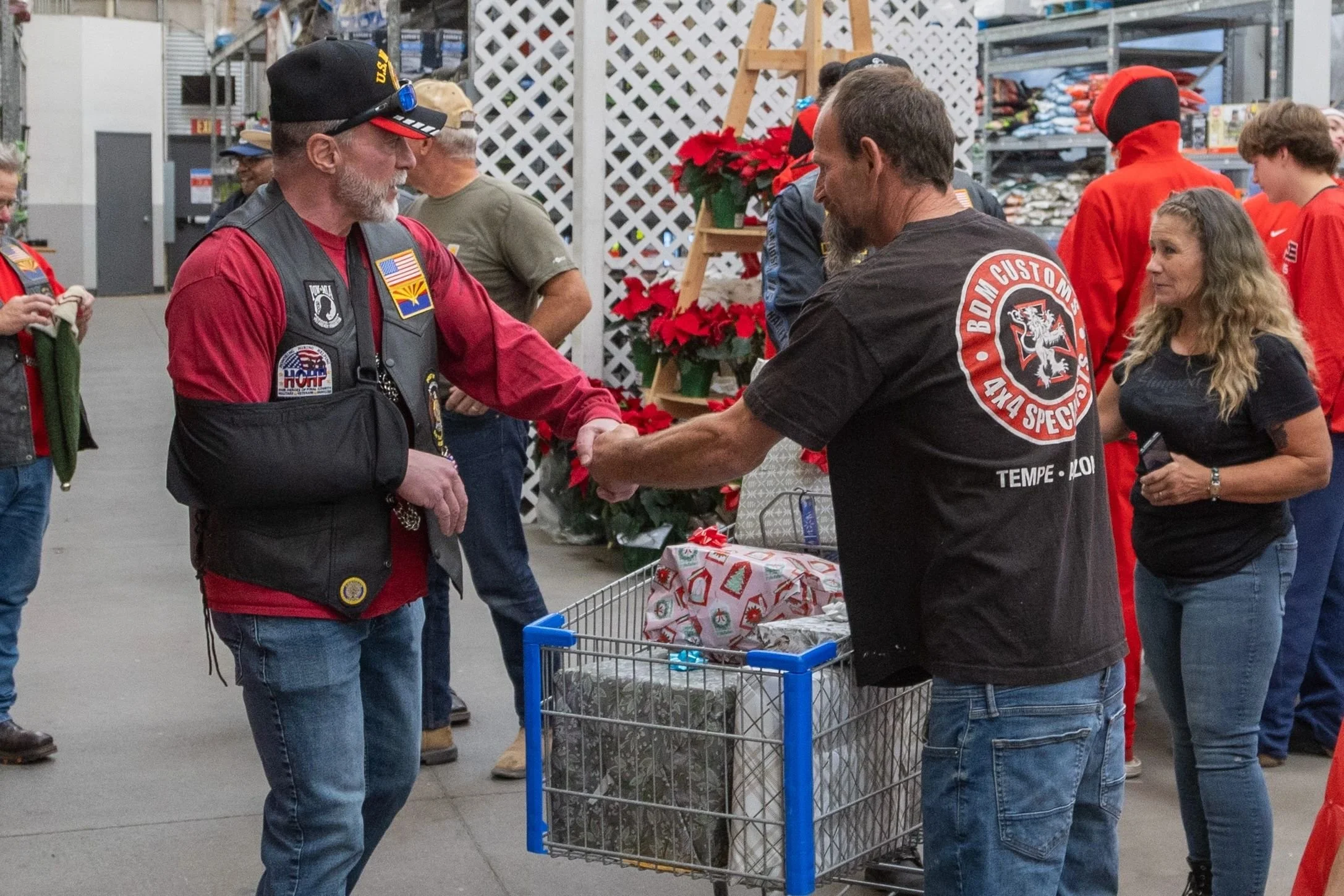 People shopping at a grocery store, engaged in conversation, with holiday decorations and supplies visible in the background.