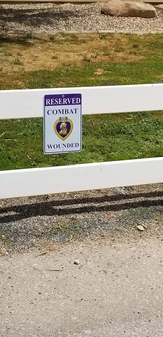 A sign on a white barricade reads "Reserved Combat Wounded" with a symbol of a heart and a soldier's profile.