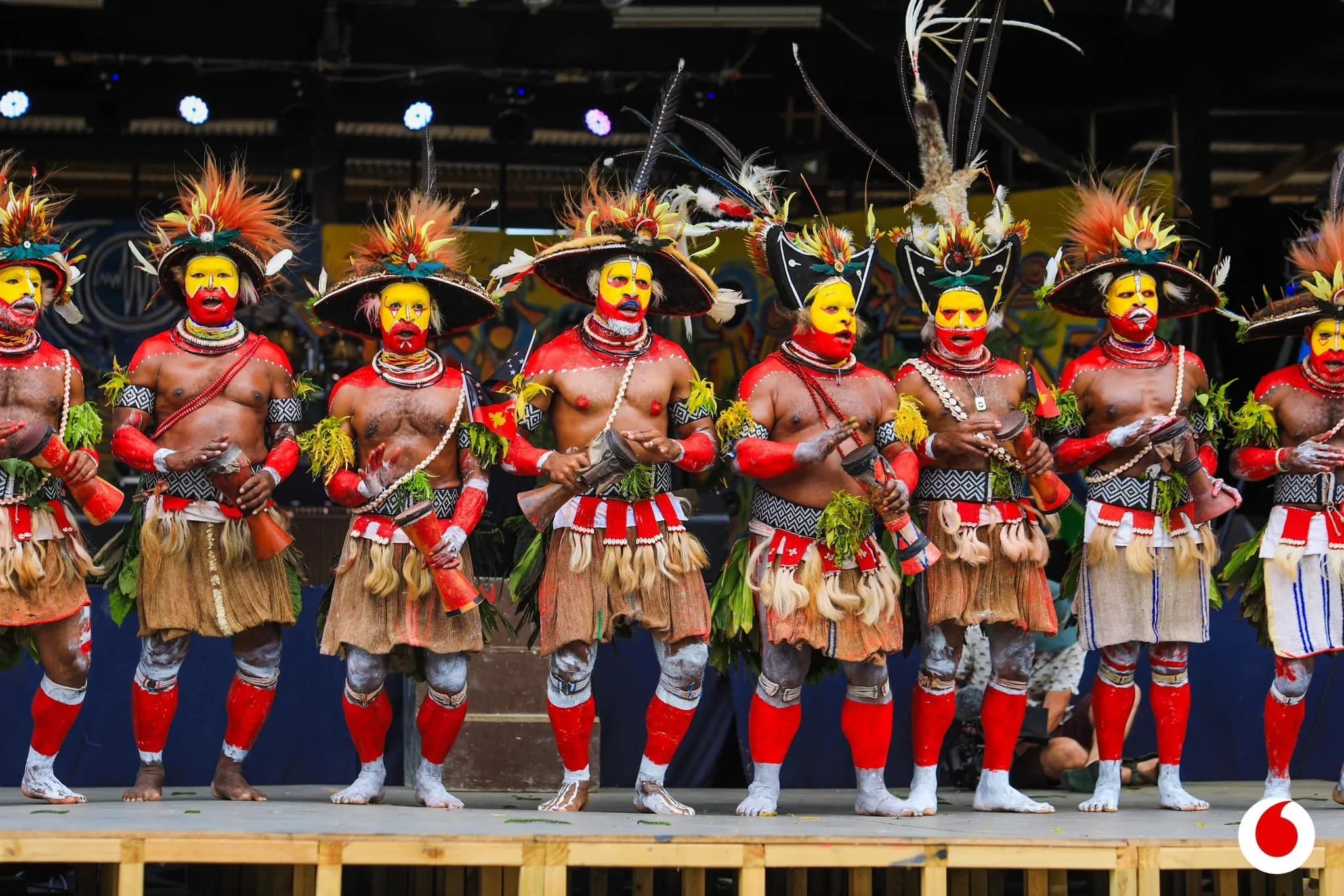 Papua New Guinean performers in colorful traditional costumes and feathered headdresses on stage