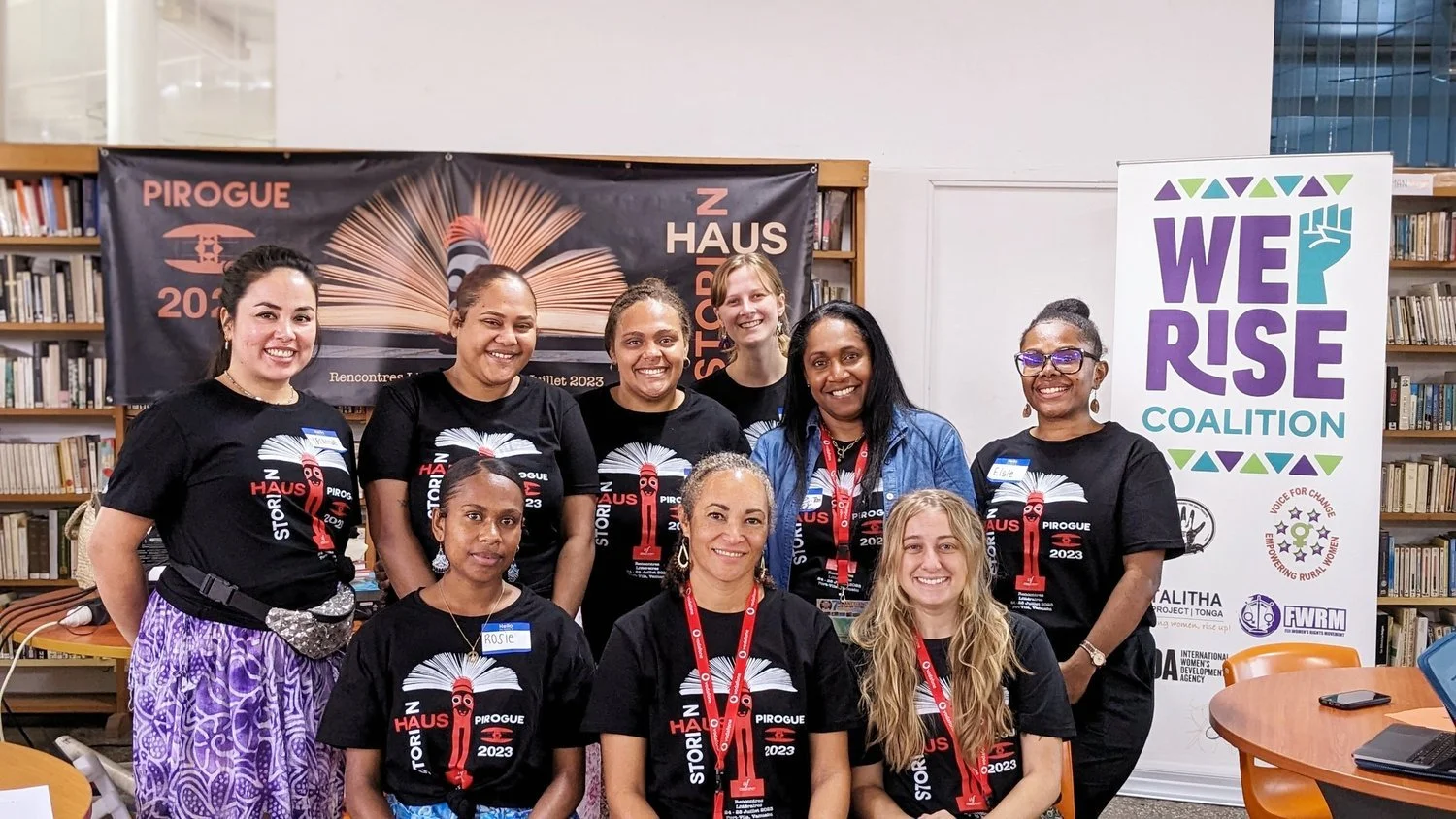Stor Haus Pirogue 2023 shirts in front of We Rise Coalition and Pirogue event banners.
