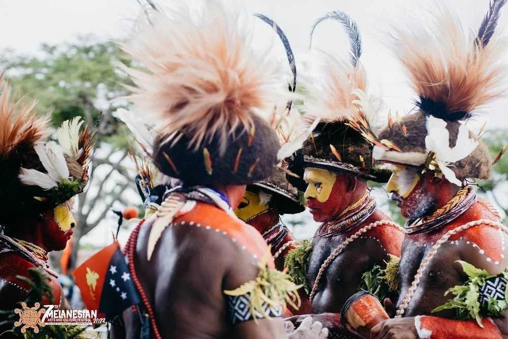 Papua New Guinean performers in traditional feathered headdresses, body paint, and ceremonial attire at the Melanesian Arts and Cultural Festival.