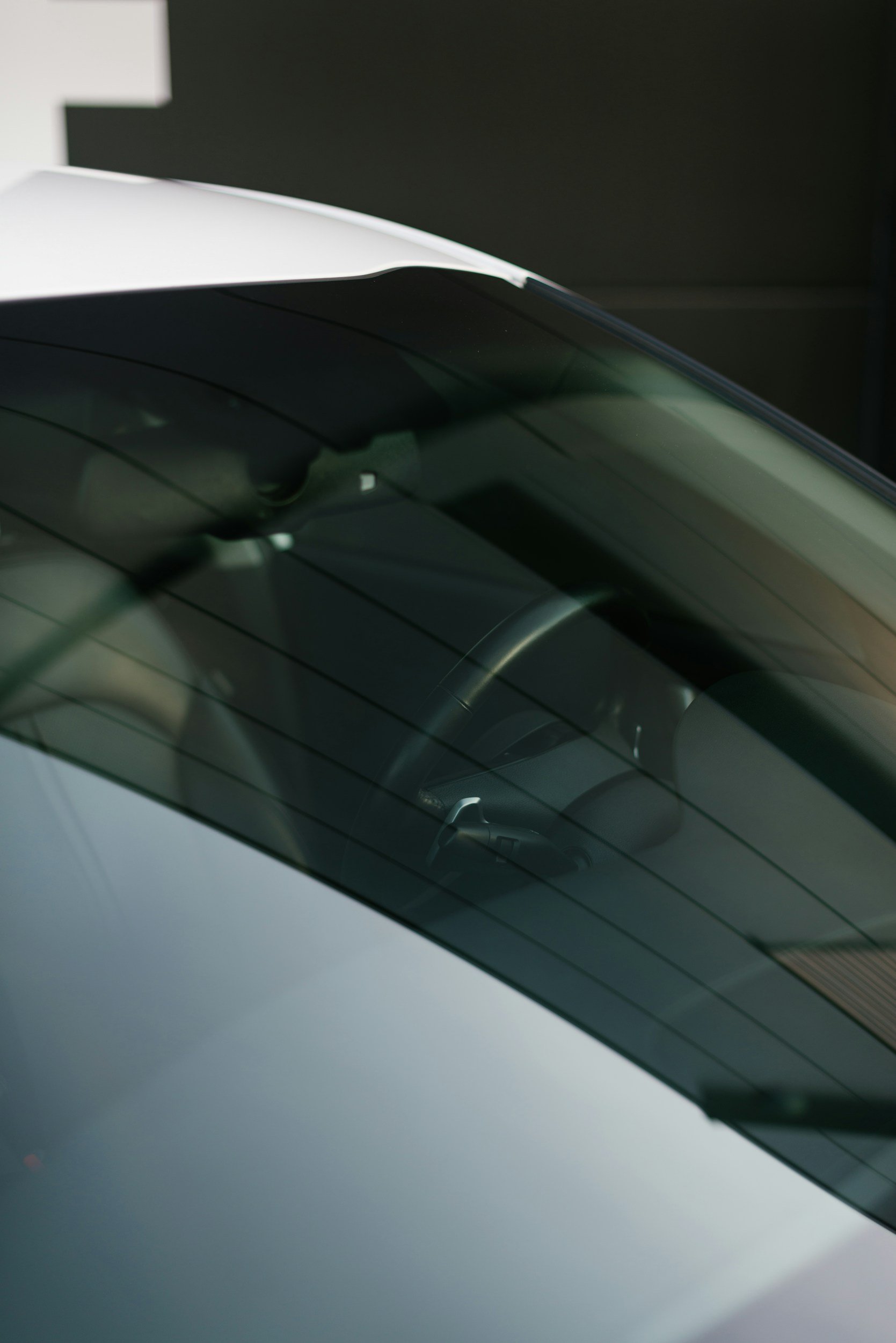 Close-up of a car's rear windshield with a visible reverse camera mounted in the center and the reflection of the car's interior on the glass.