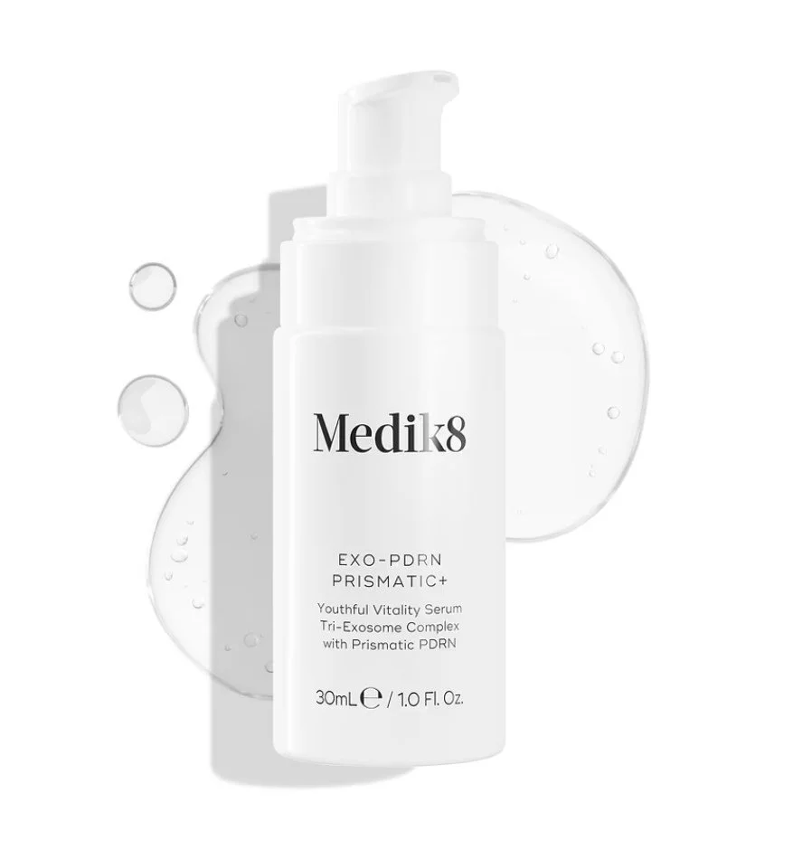 A white bottle of Medik8 EXO-PDRN PRISMATIC+ youth serum with a pump dispenser, surrounded by clear serum droplets on a white background.