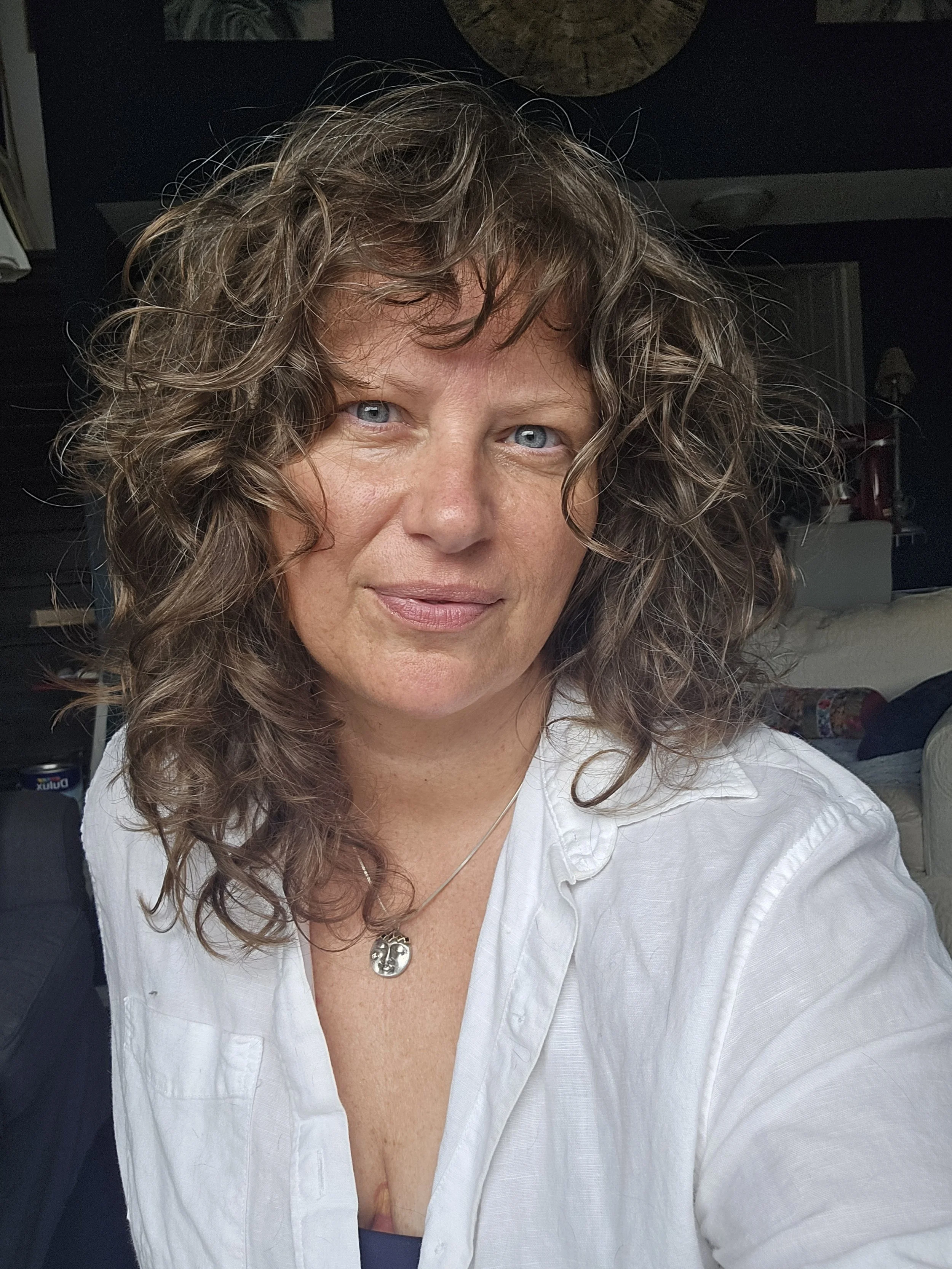 Wren wearing white with flowing curls and a clock in the background.