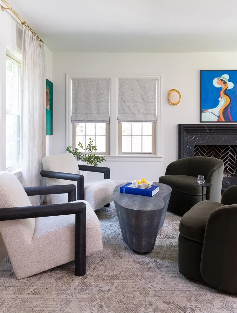 boucle chair, green chair, blue art, black fireplace, sconce, roman shade