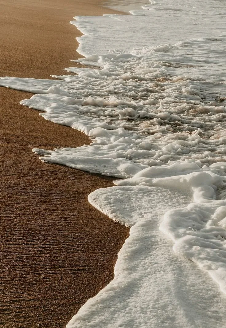 Foamy white waves washing onto a sandy beach.