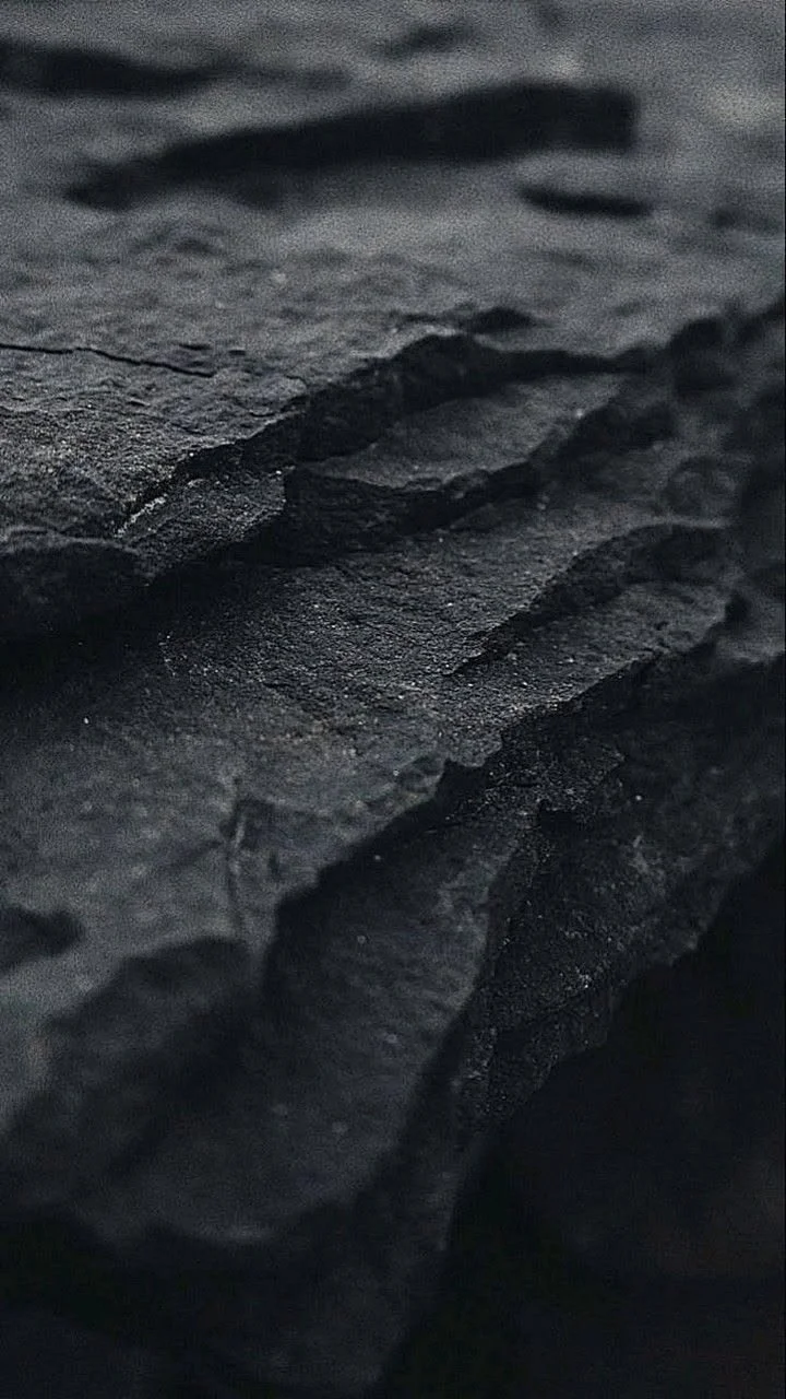 Close-up of black slate or rocky surface with rough texture and layered appearance.