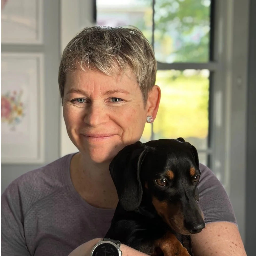 Exercise Physiologist Rachel sitting smiling with mini dachshund Max in her arms