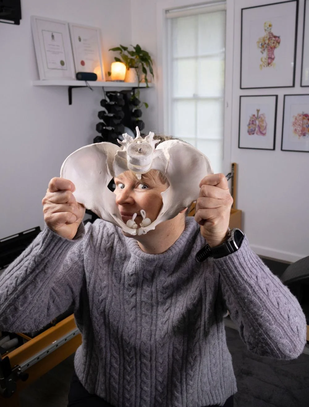 Exercise Physiologist Rachel, looking through a model pelvis with a cheeky look