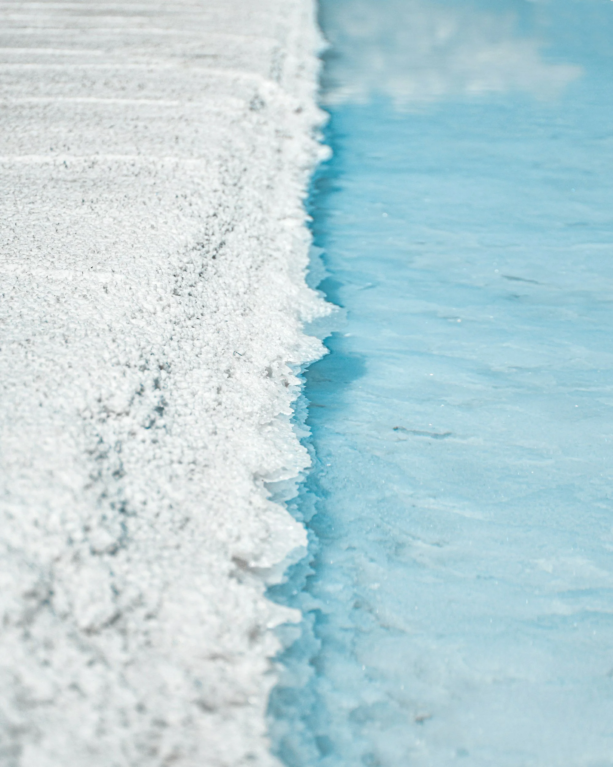 Close-up of snow and ice on a frozen surface with a thin layer of snow on top of ice.
