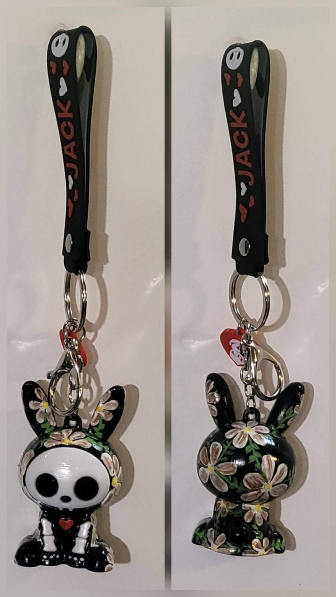 Cute black bunny-shaped keychain with white and floral accents, hanging from a key ring, with the front and back views.
