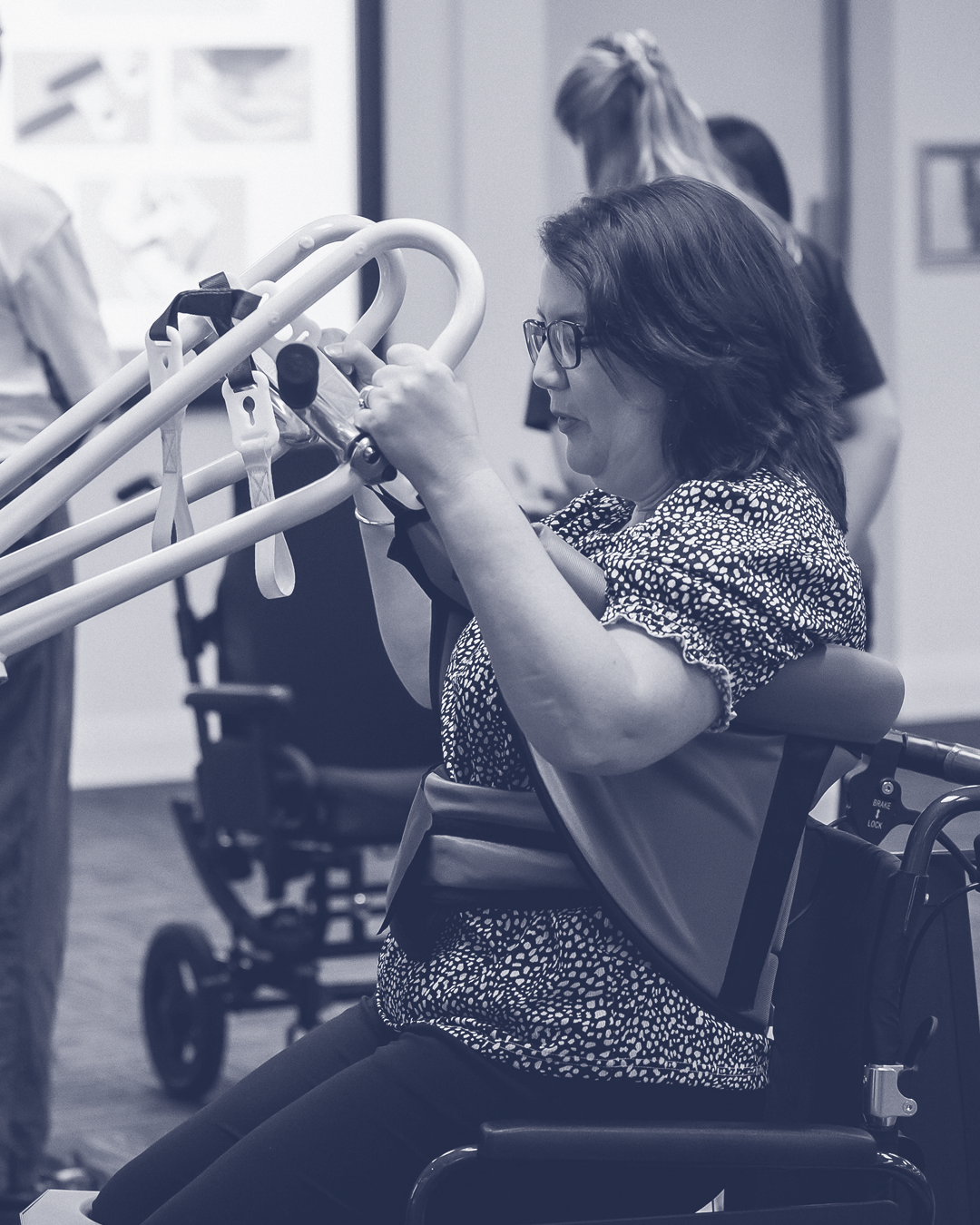 Woman in a wheelchair using a communication device in a medical setting.