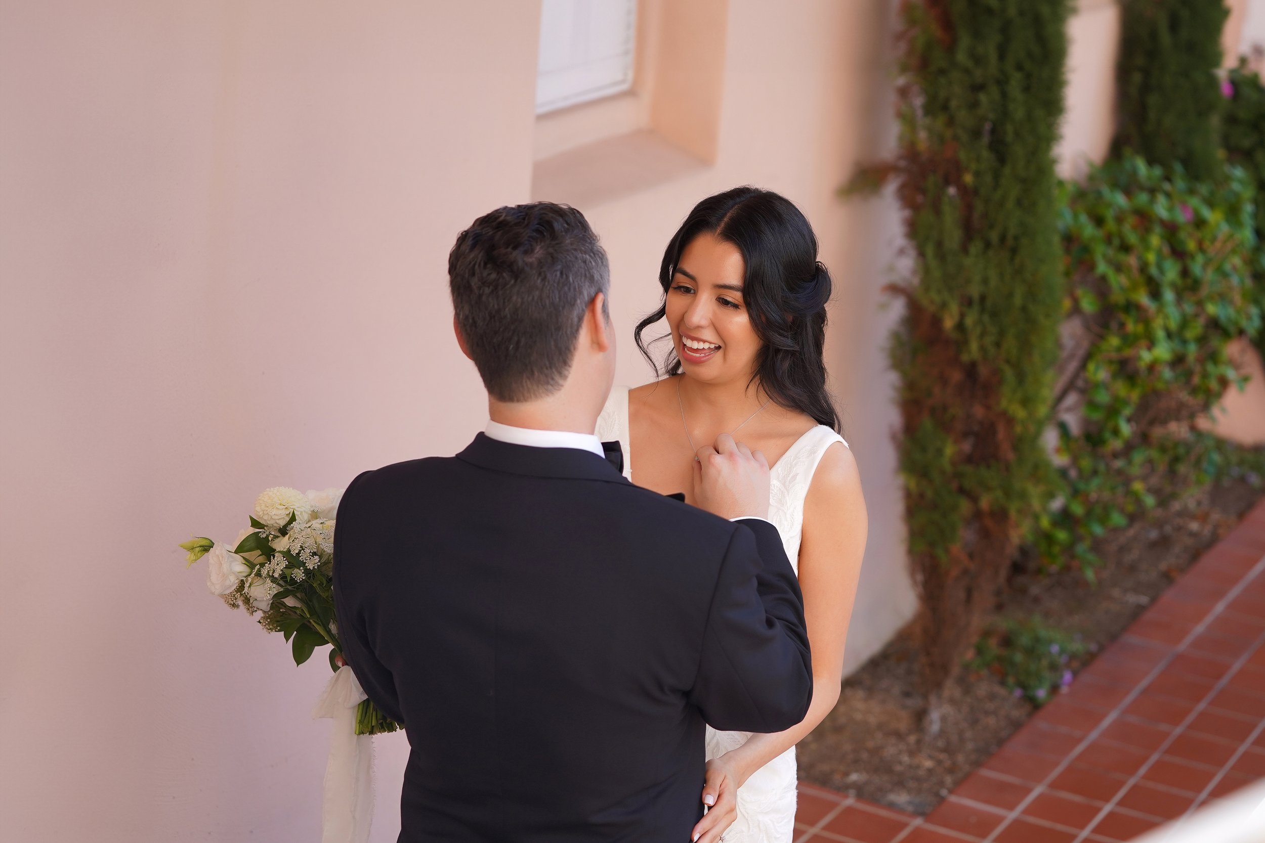 Close-up of a smiling bride looking at her groom during their first look wedding portrait by the pink exterior walls at La Valencia Hotel in La Jolla, San Diego.