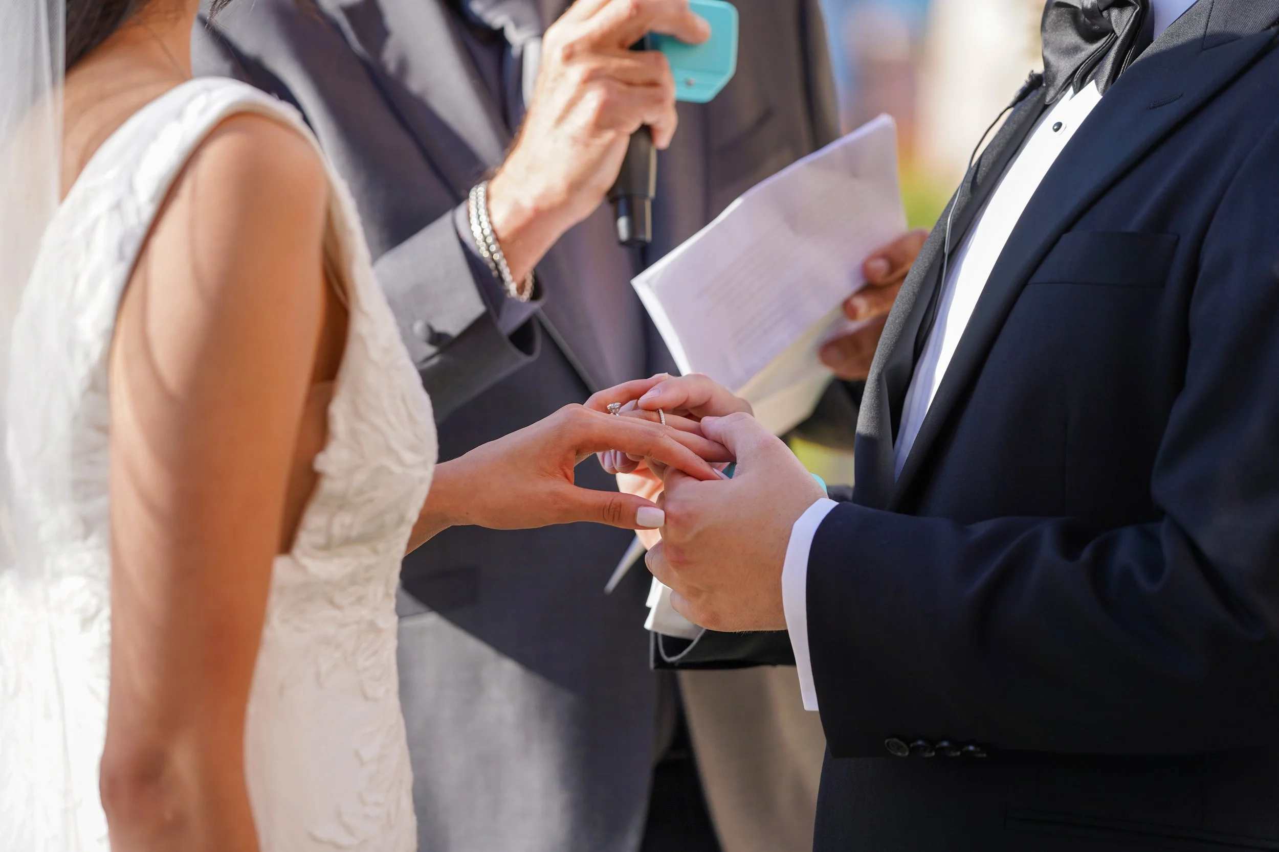 Close-up of a groom placing a wedding band on the bride's finger during a wedding ceremony at La Valencia Hotel in La Jolla, San Diego.
