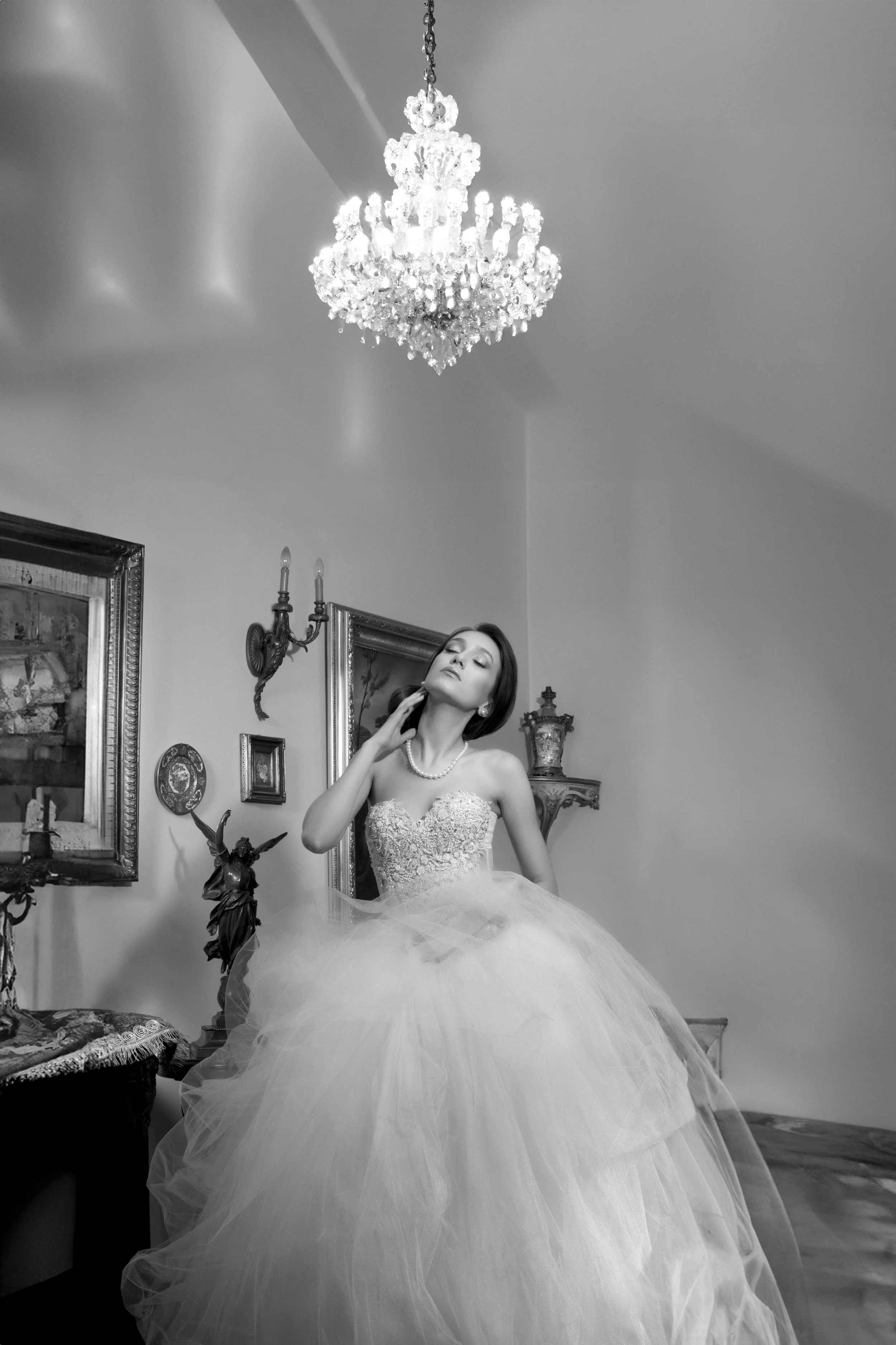 Fine art black and white wedding photography featuring a model posing in an elegant room filled with vintage European decor and art.