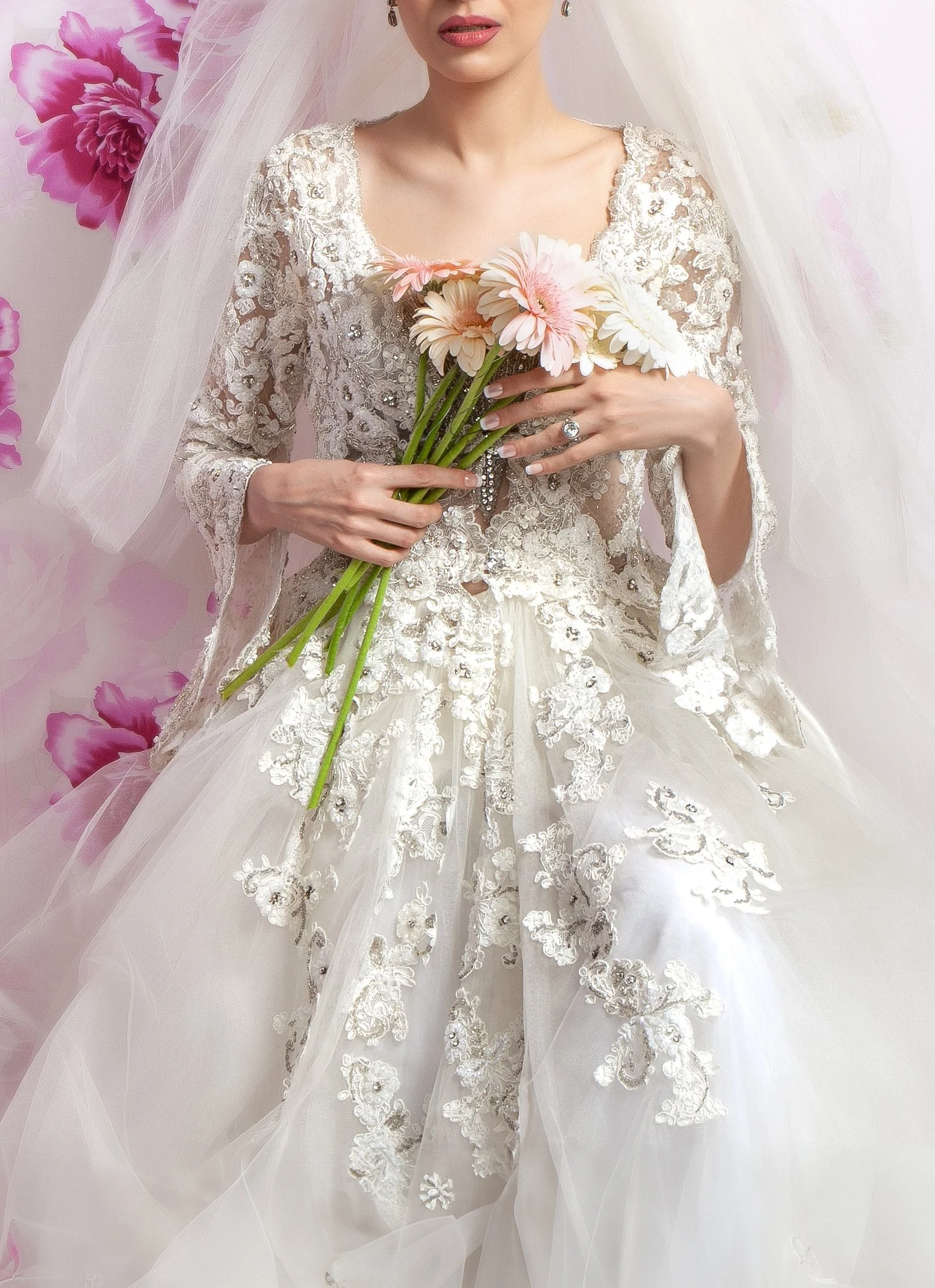 Embroidered floral lace bridal gown featuring sheer long sleeves, scoop neck, and a voluminous layered tulle skirt.